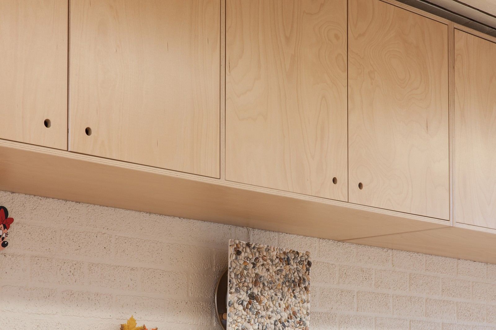 Detail van twee kastdeuren in berken multiplex met greepgaten.