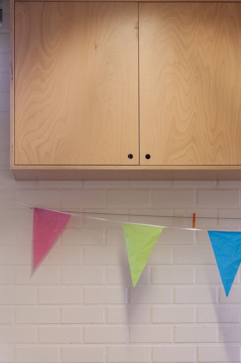 Detail van kastdeuren in berken multiplex met greepgaten en zichtbare fineertekening.