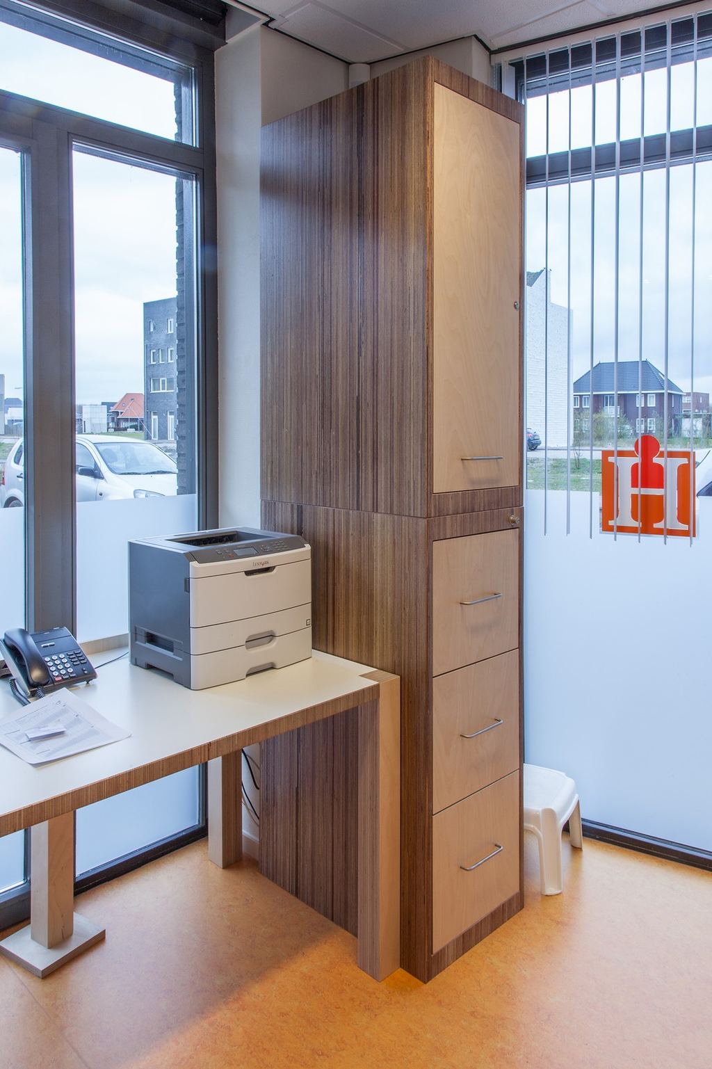 Kolomkast in meranti plexwood met berken multiplex deuren en laden, naast een bureau.