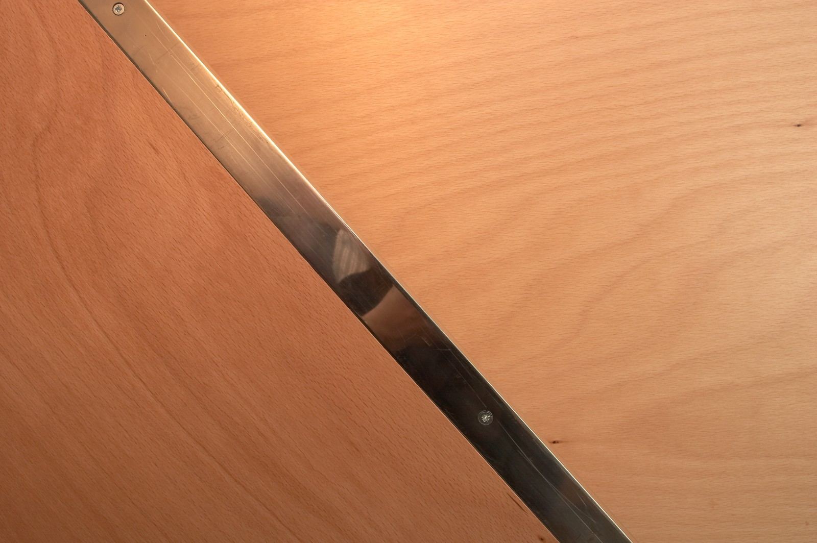 Close-up van de stalen rand langs een beuken multiplex trede.
