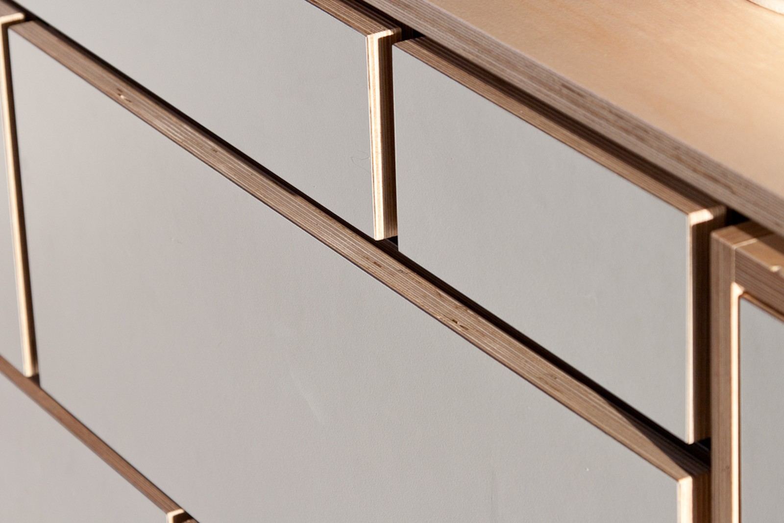 Detail van de verstekverbinding in de lichtgrijze fronten van de buffetkast.