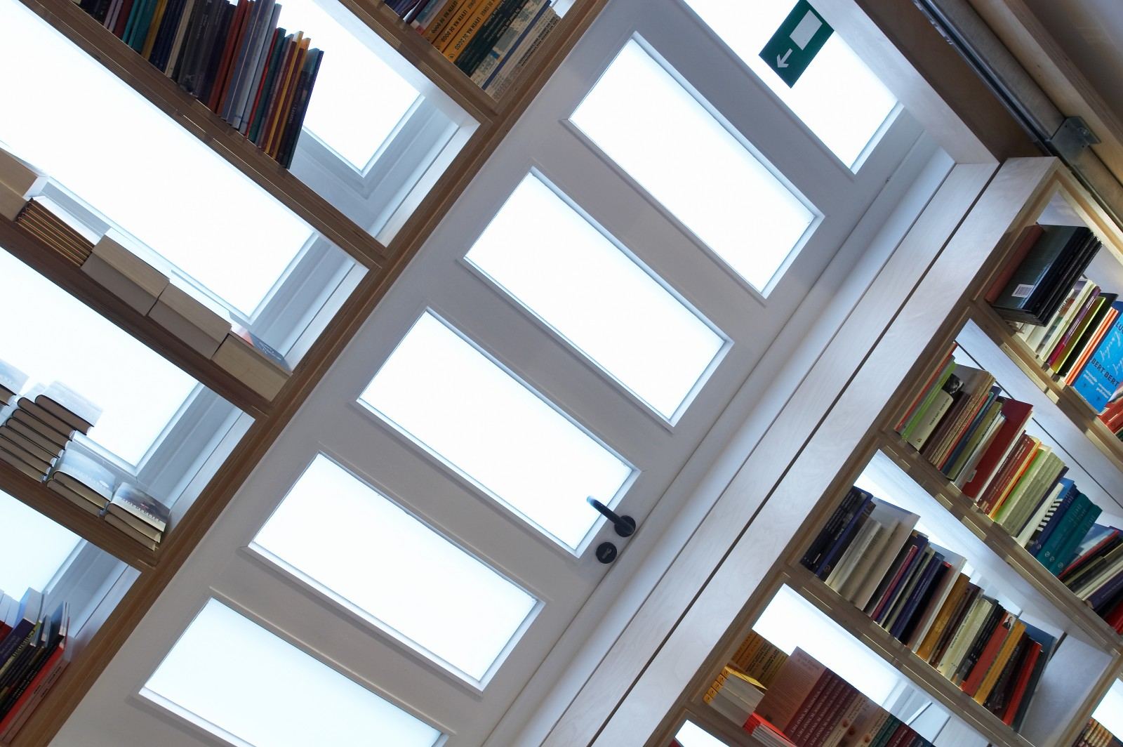 Boekenkast met een diagonaal aflopende bovenkant, hoog tegen het plafond.