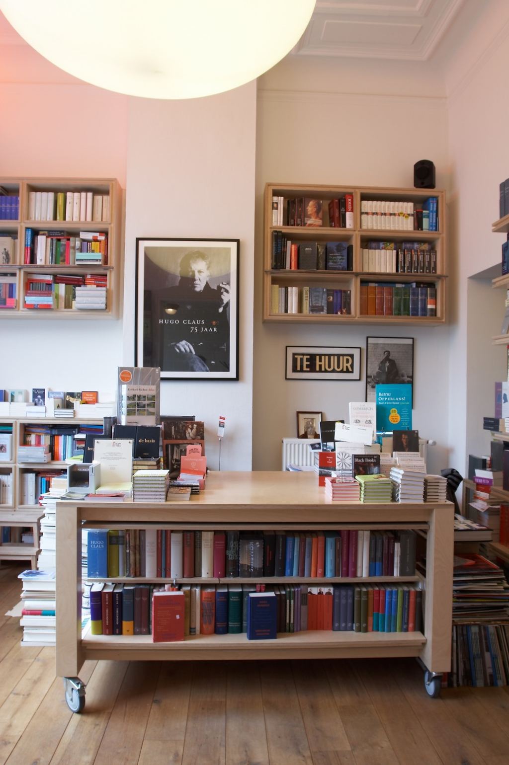 Zwevende boekenkastjes naast een verrijdbaar tafeltje met een boekenplank eronder.