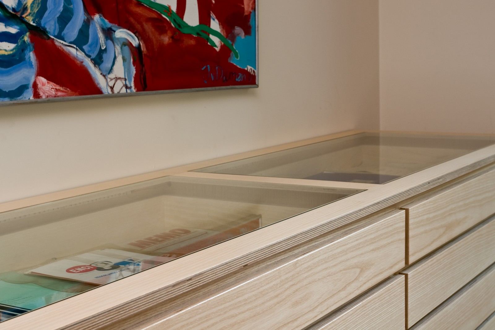 Detail van een glazen vitrine en een open lade met een oud reclamebord en een stripverhaal.