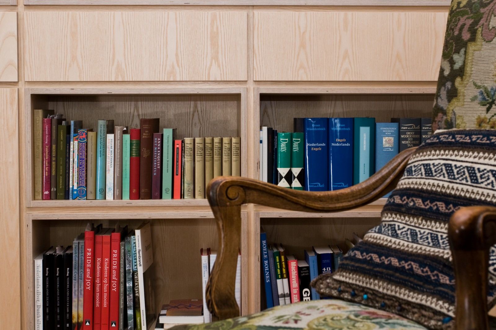 Detail van twee open boekenvakken in de kast van essen fineer.