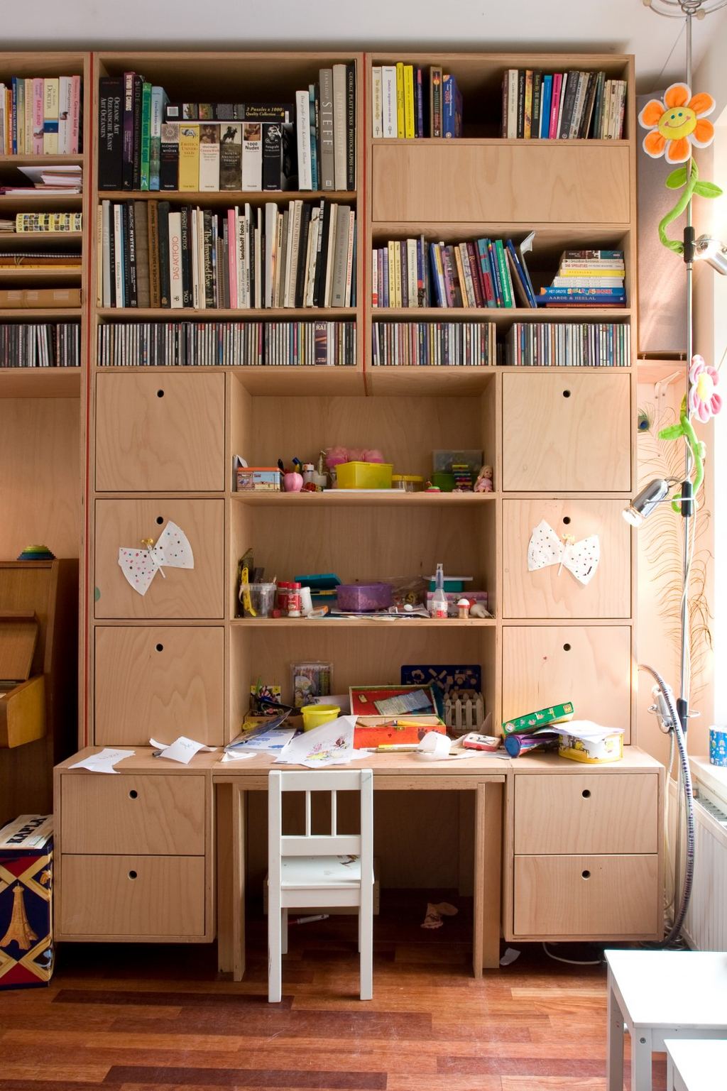 Wandkast met open vakken vol boeken, boven kastjes en een ingebouwd bureau.