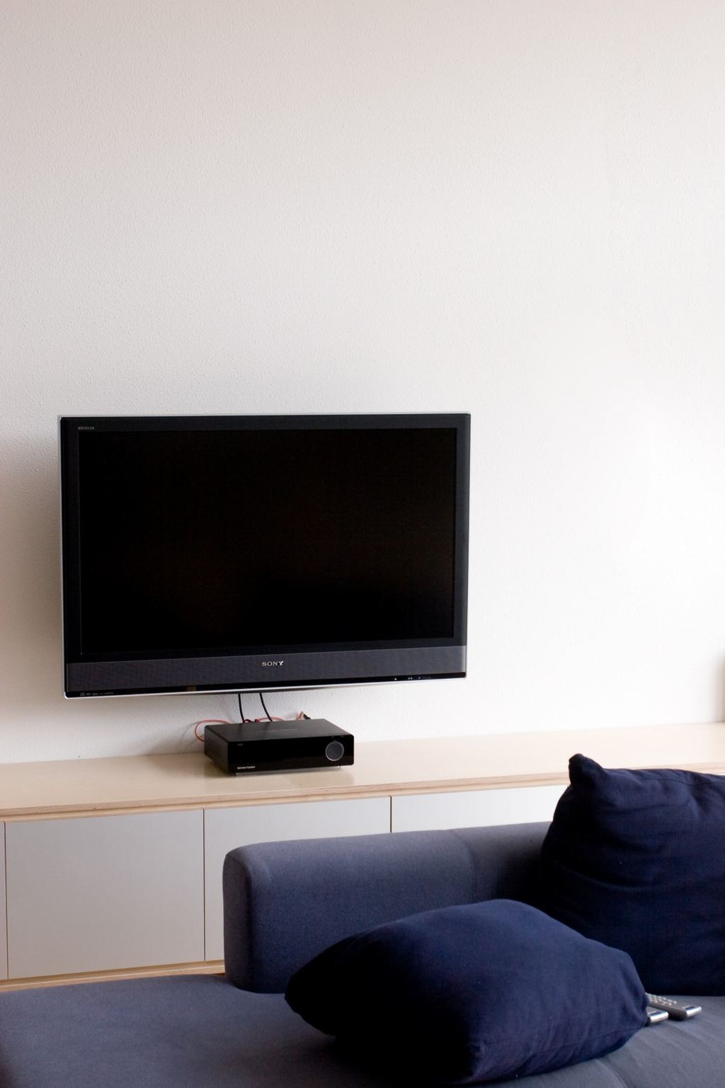 Laag dressoir met aluminium HPL-fronten onder een wandgemonteerde televisie.