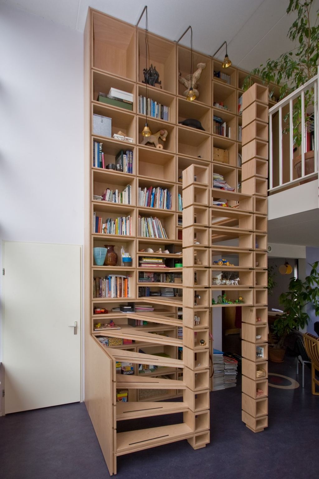 Kastenwand met ingebouwde trap die als een puzzel in elkaar grijpt.