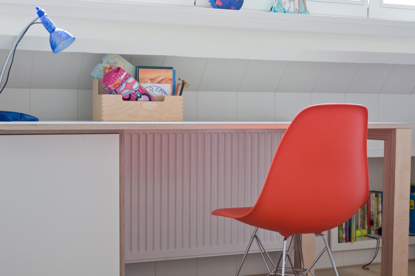 Kinderbureau van berken multiplex en wit HPL onder een schuin plafond.
