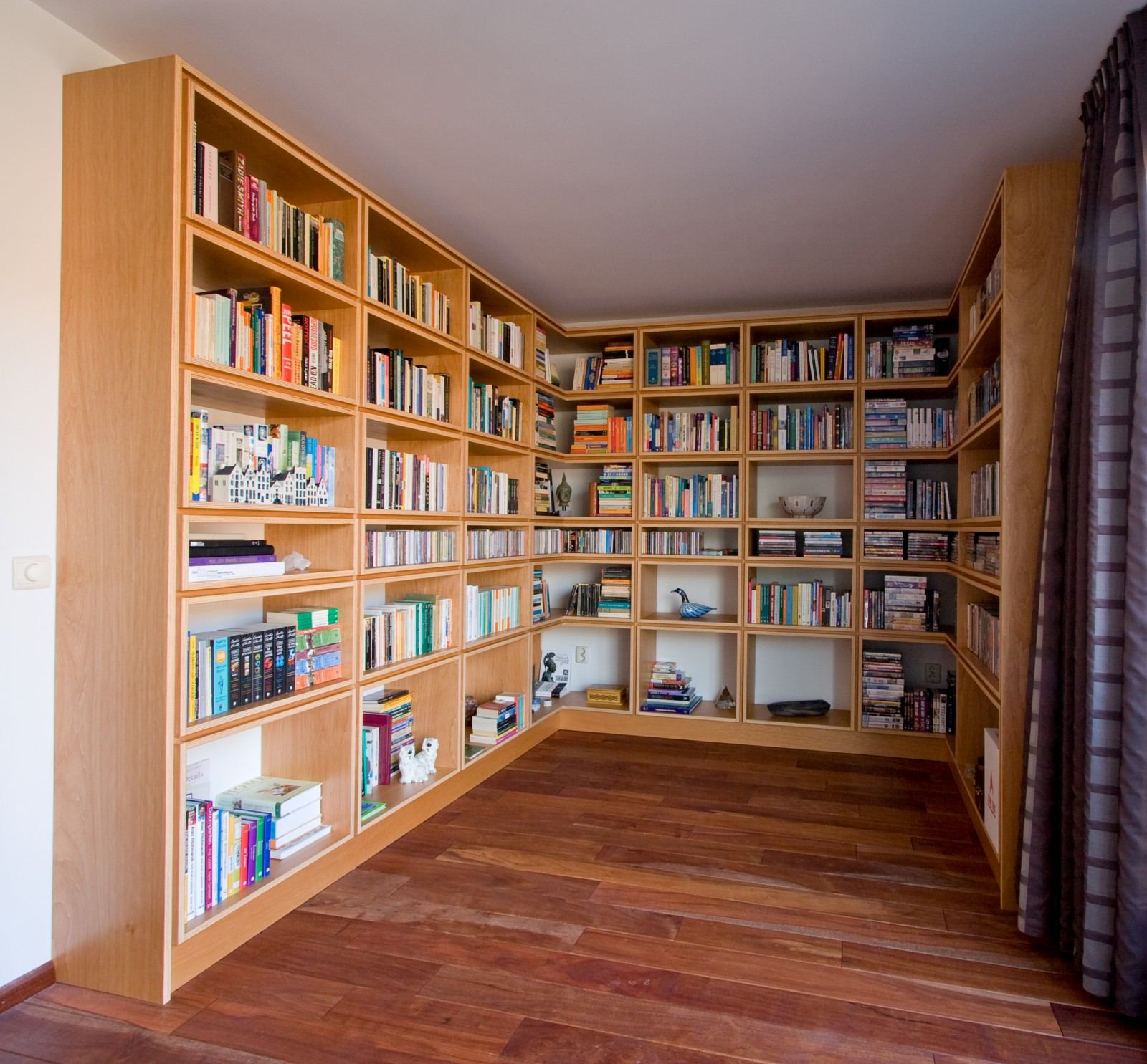 Wandvullende boekenkast zonder achterwand, met een raster van open vakken.
