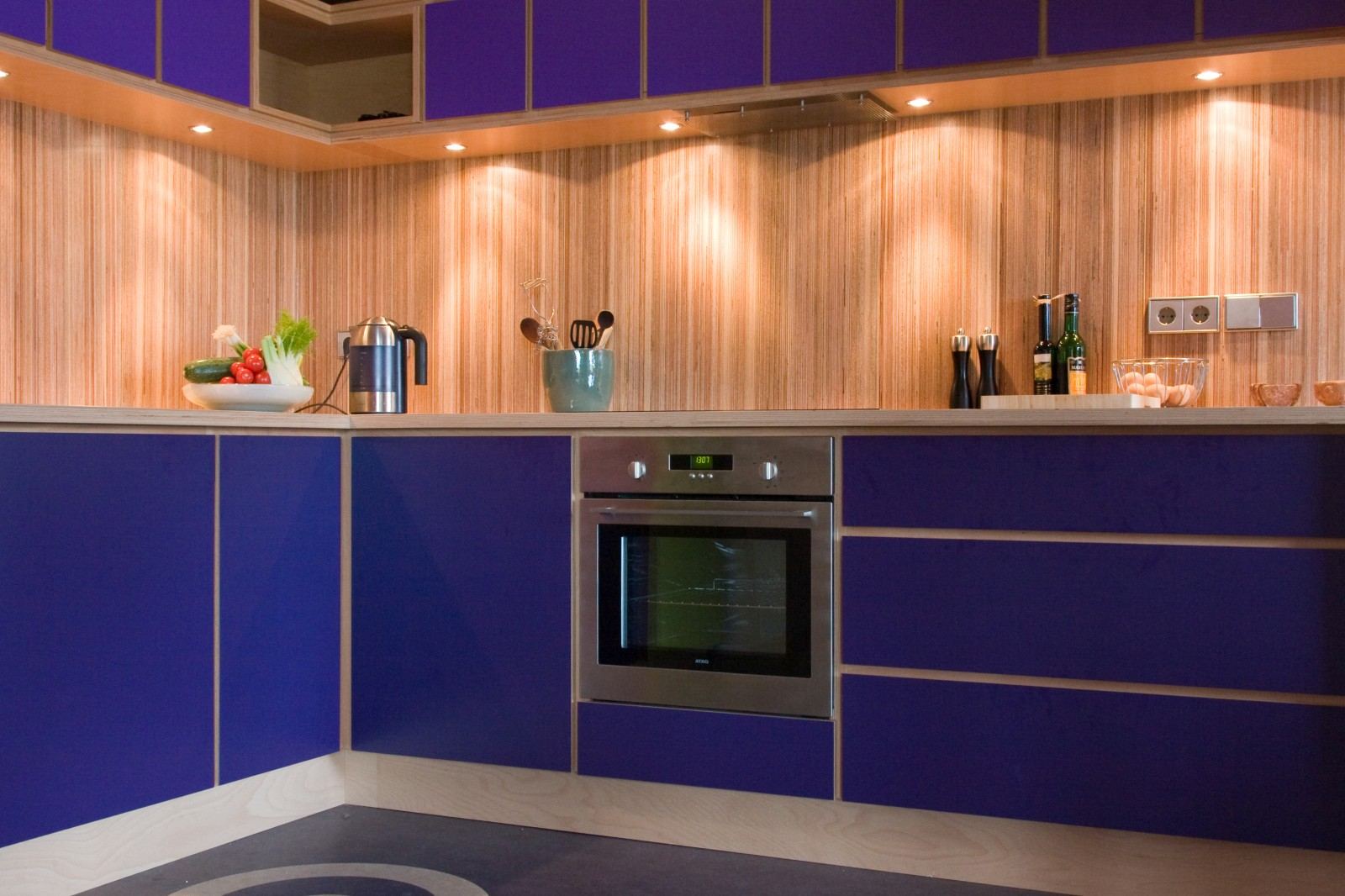 Open keuken met paarse kastfronten en een wand van gestreept plexwood.