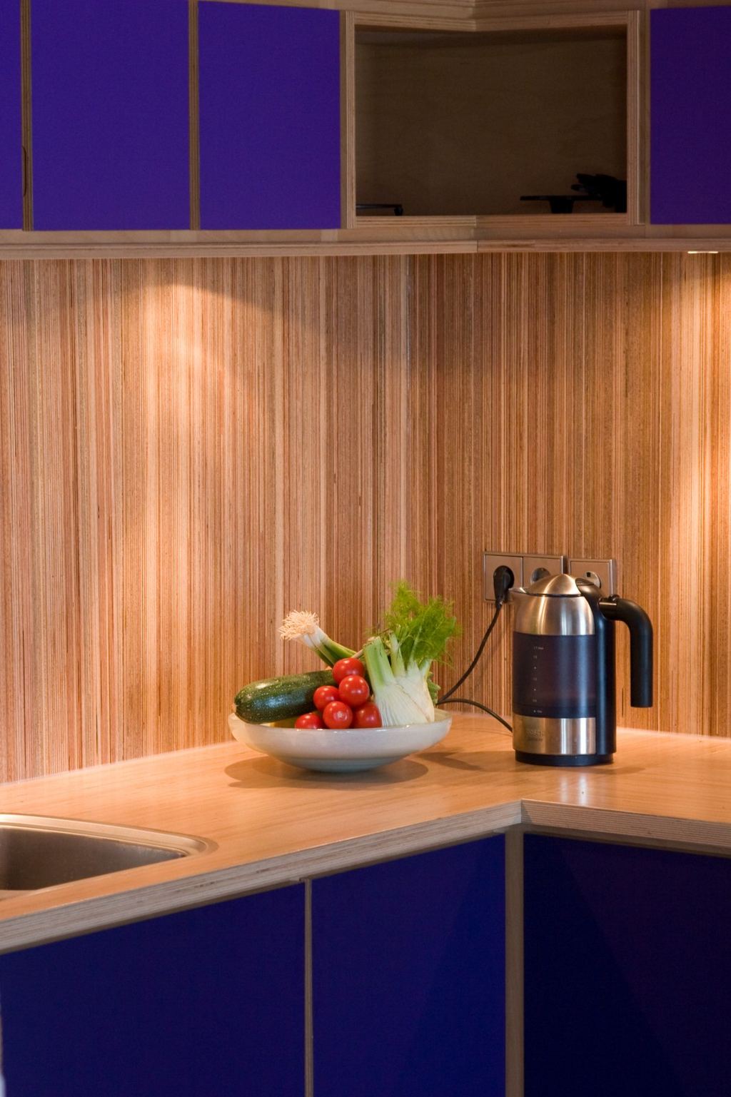 Hoekkast met paarse fronten boven een werkblad van gestreept plexwood.