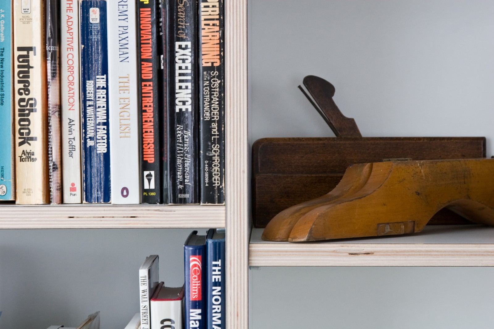 Boeken en oude houten gereedschappen op een open plank.