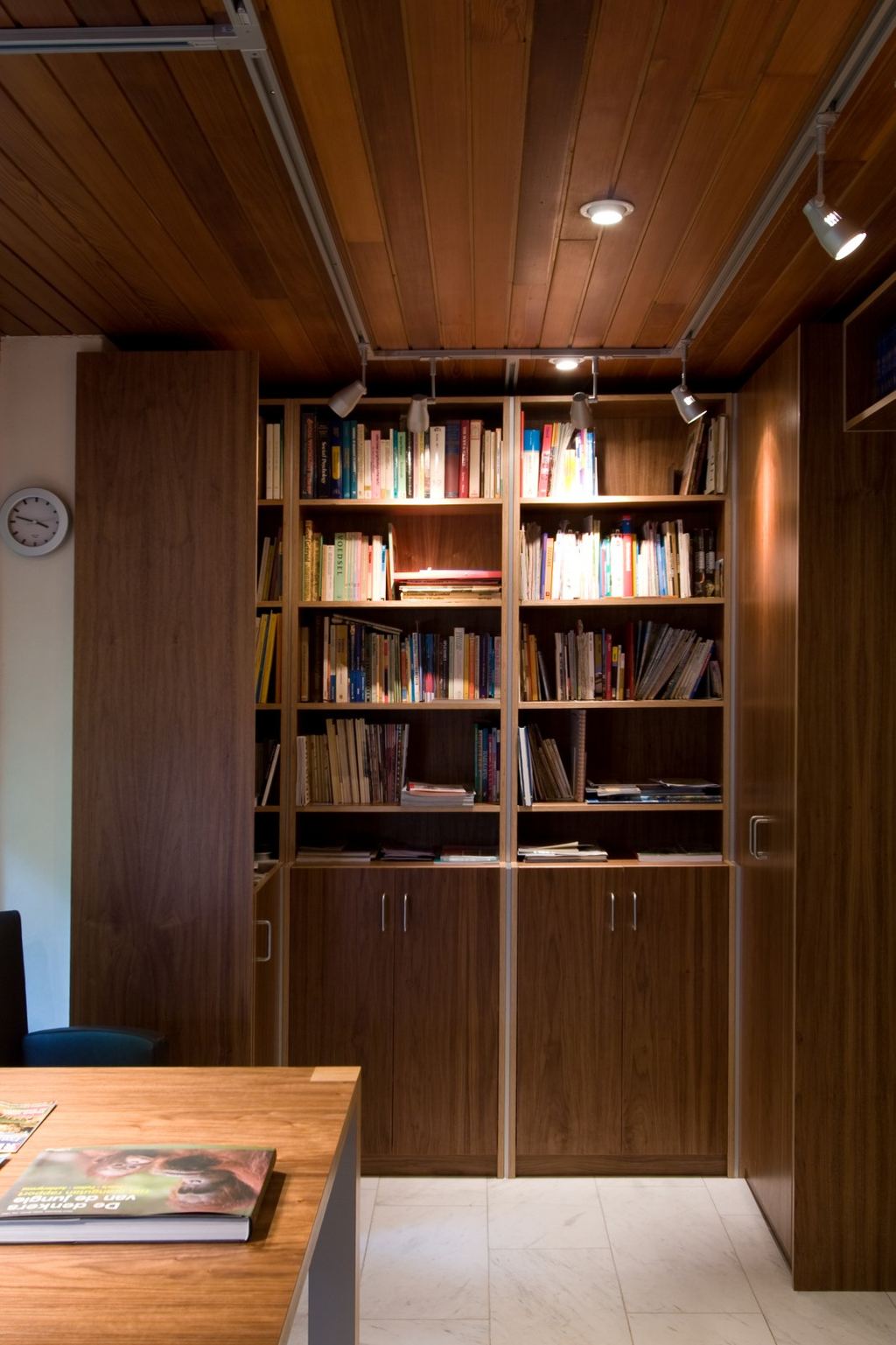 Boekenkast met noten fineer boven gesloten kastdeuren met metalen grepen.