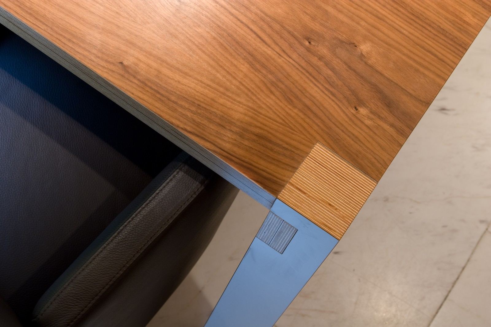 Detail van de tafelpoot met noten fineer en aluminium inleg.