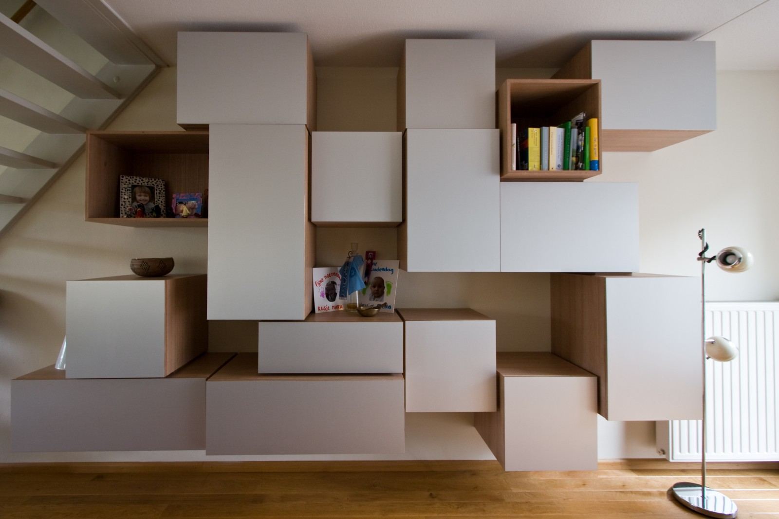 Puzzelvormige wandkast met losse vierkante en rechthoekige vakken in lichte houtkleur.