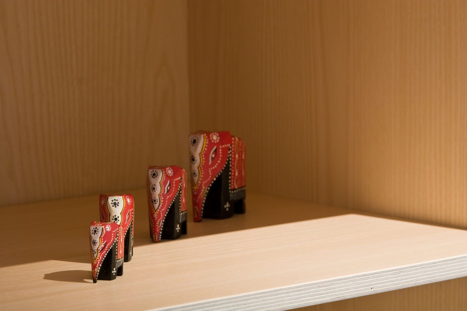 Detail van een houten plank met een setje beschilderde houten olifantjes.