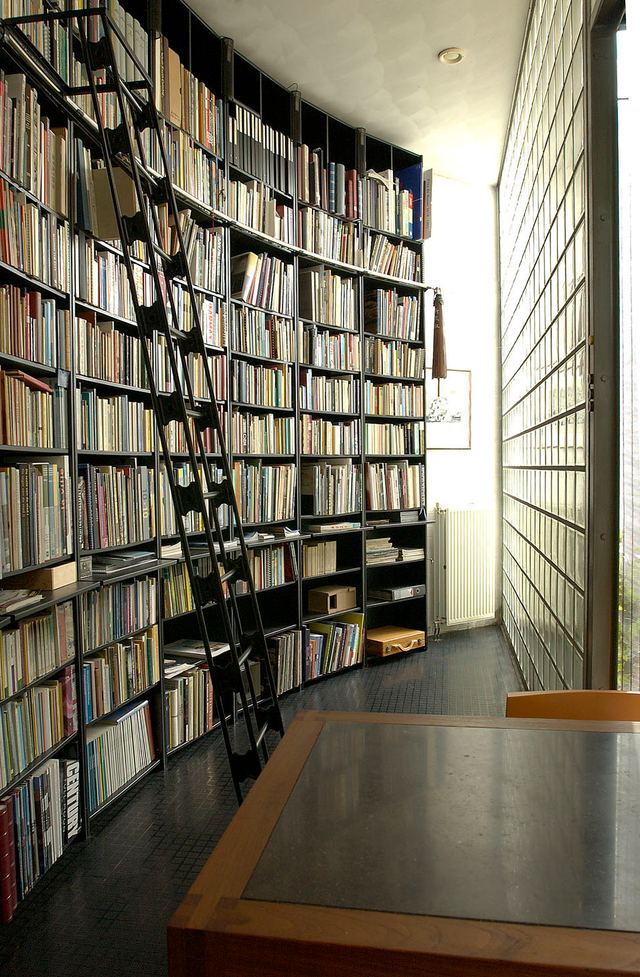 Gebogen, zwarte boekenkast met een op maat gemaakte bibliotheektrap.