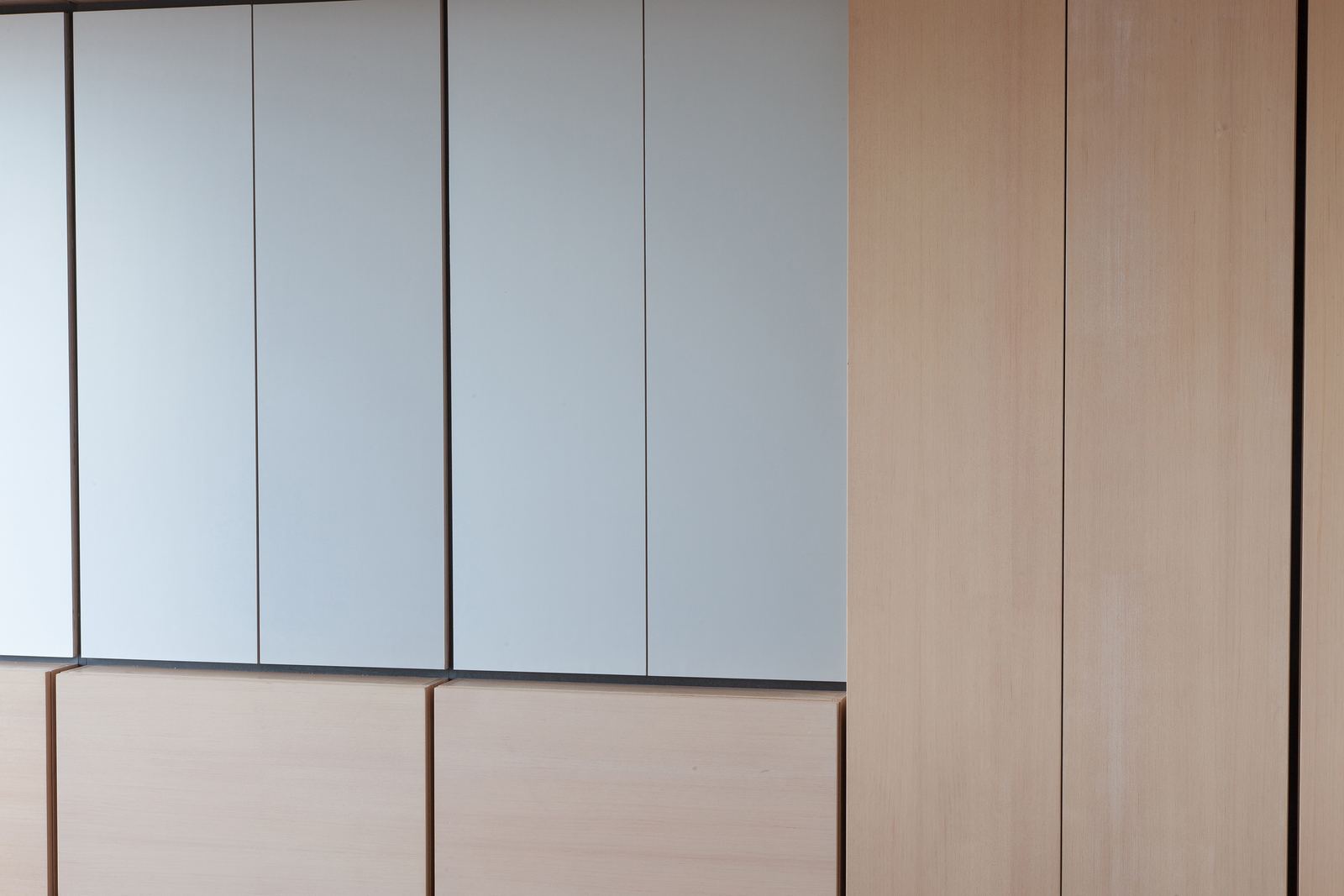 Detail van aluminium deuren naast een eiken kastdeur.