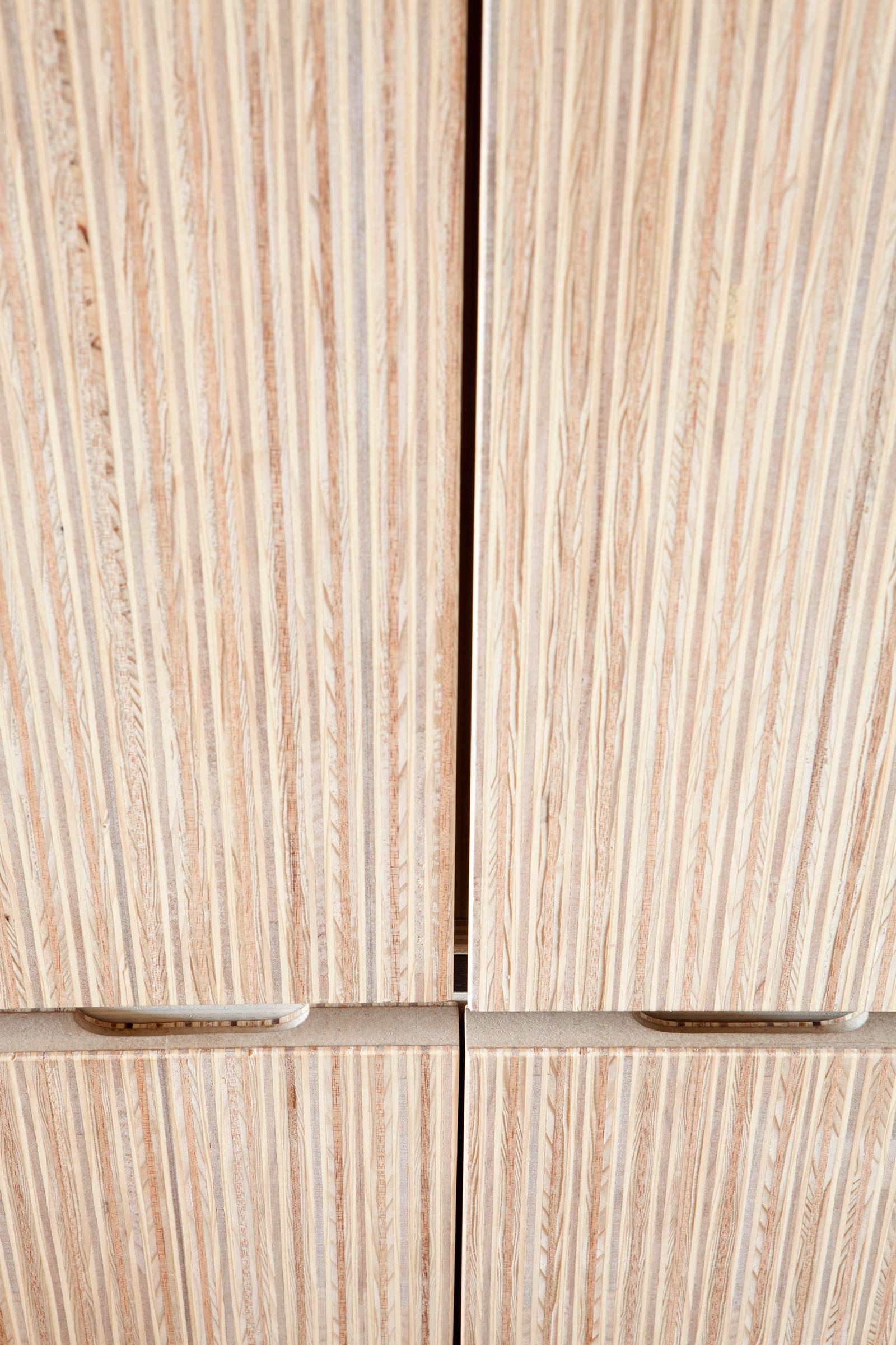 Detail van de uitgespaarde grepen tussen twee plexwood kastdeuren.