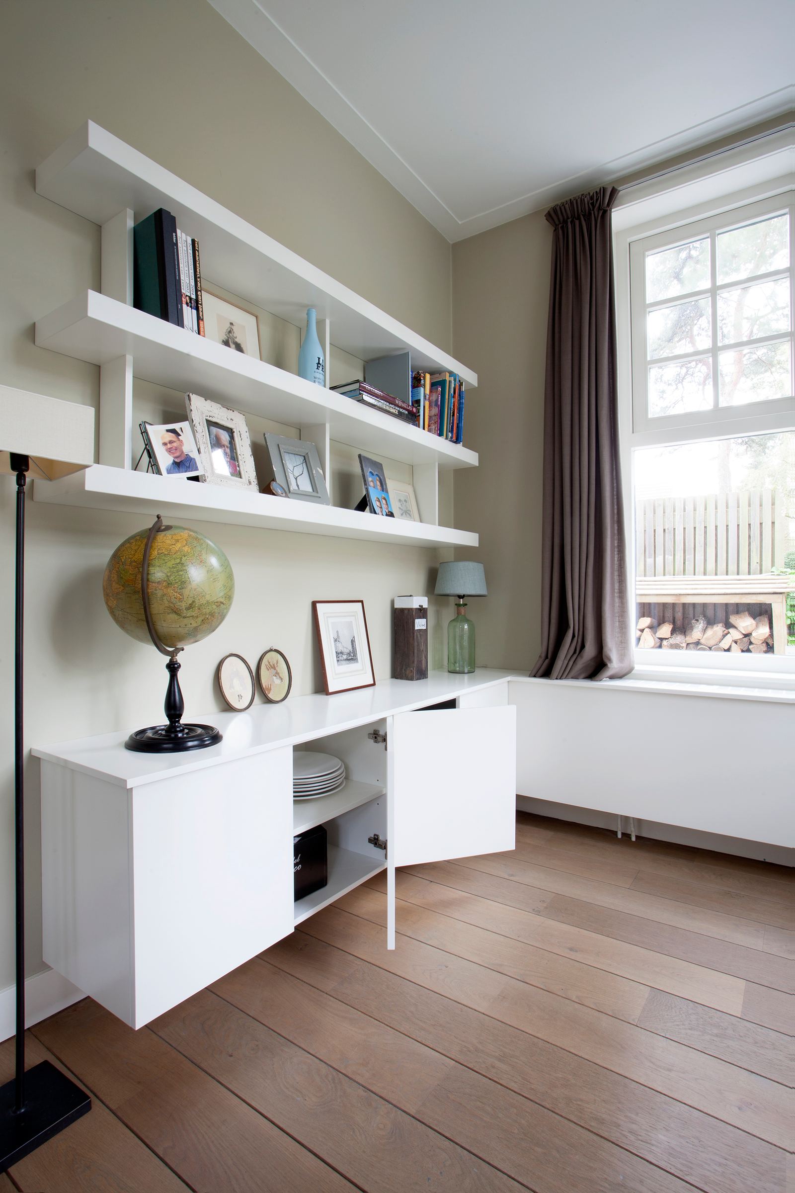 Dressoir met een geopende deur en servies eronder de planken.