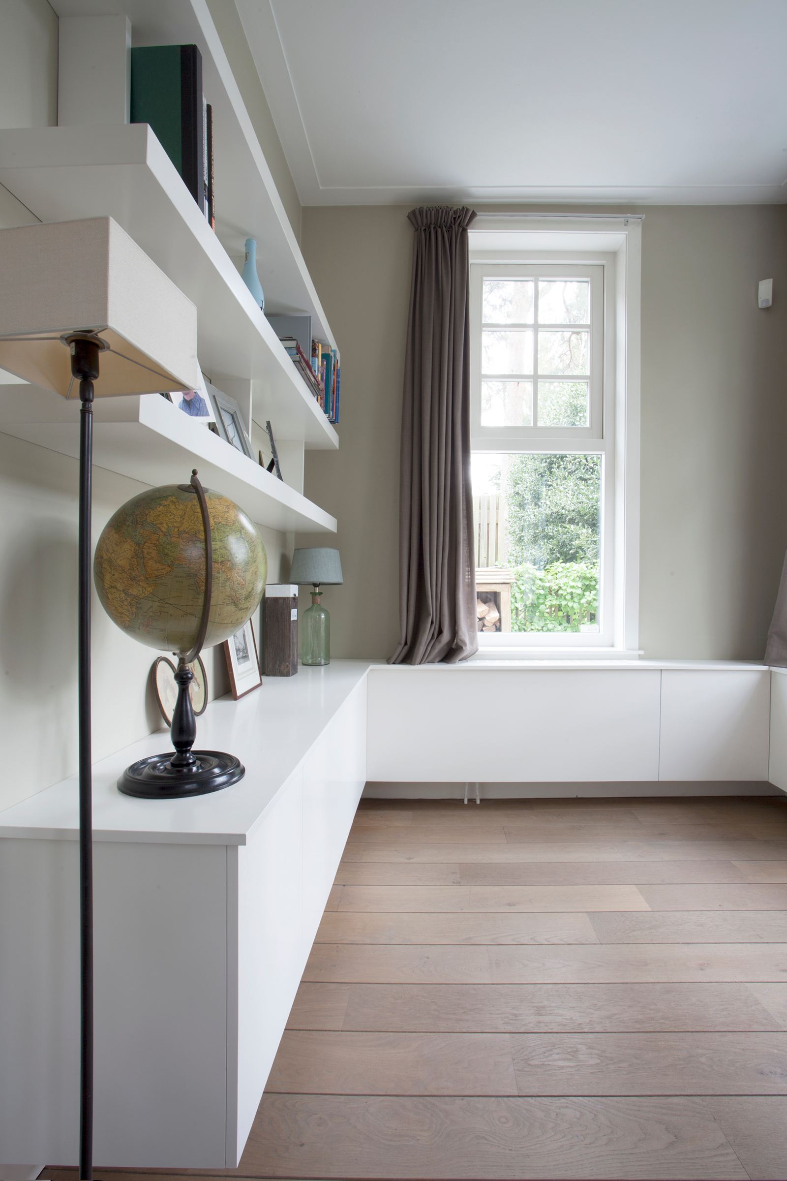 Zwevende planken en een wit dressoir langs de wand.