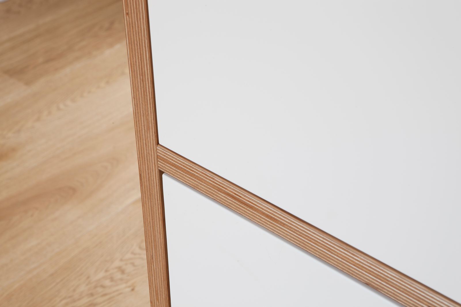 Detail van de eiken hoekverbinding tussen twee witte kastdeuren.
