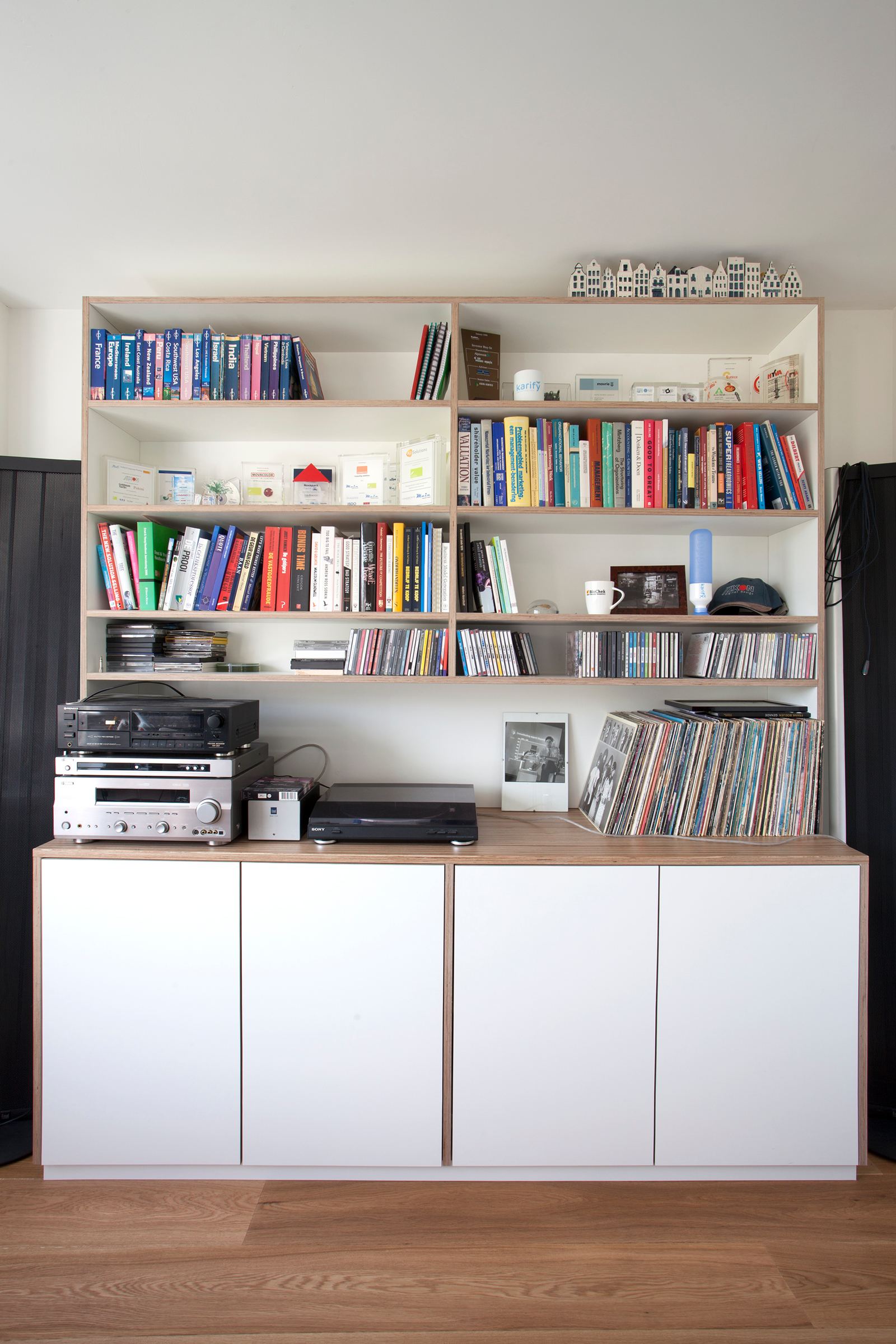 Wandkast met open boekenplanken boven een gesloten kast met witte deuren en een houten blad.