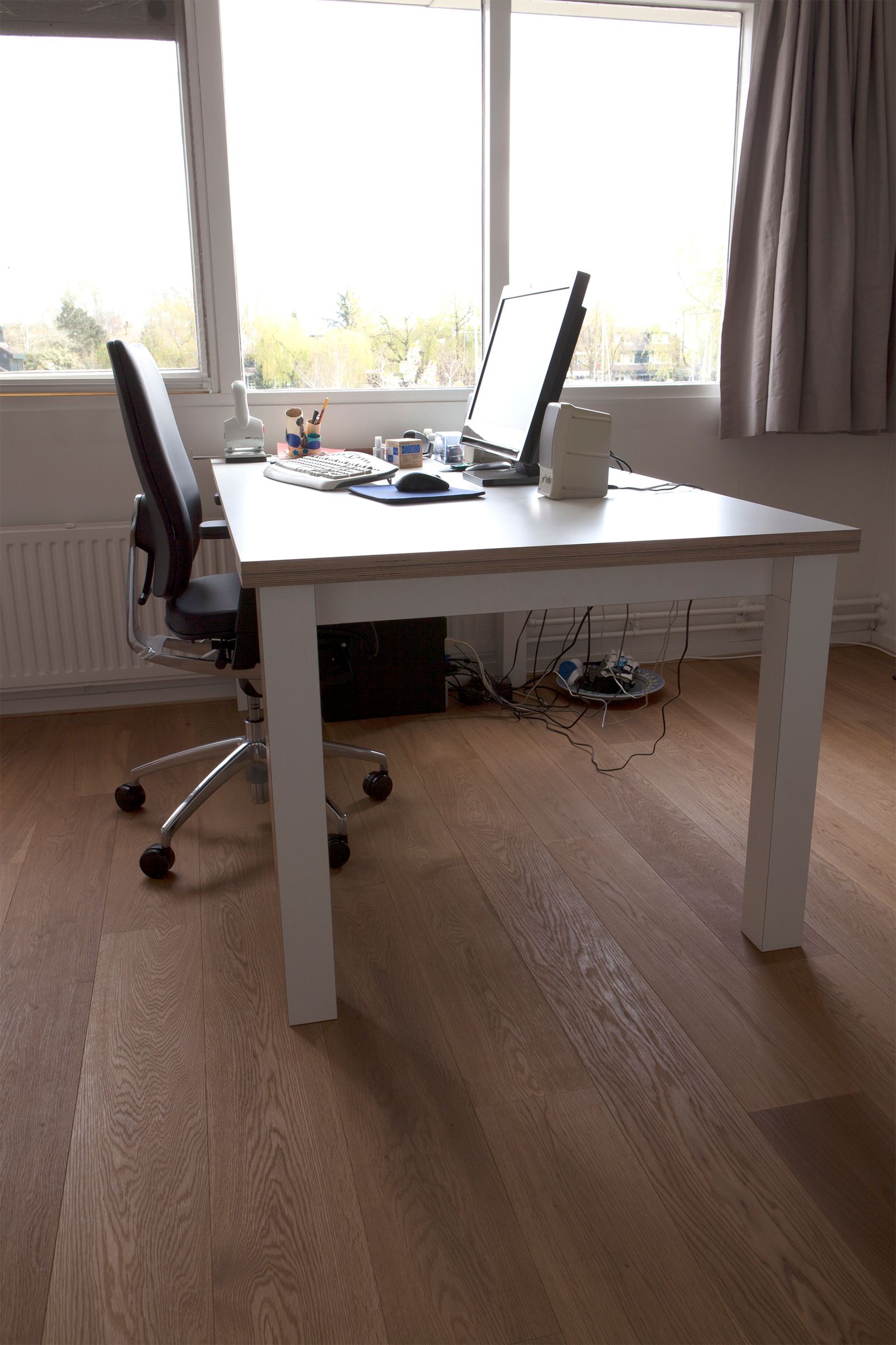 Rechthoekige tafel met een wit blad en een gestreepte houten rand, met een bureaustoel ernaast.
