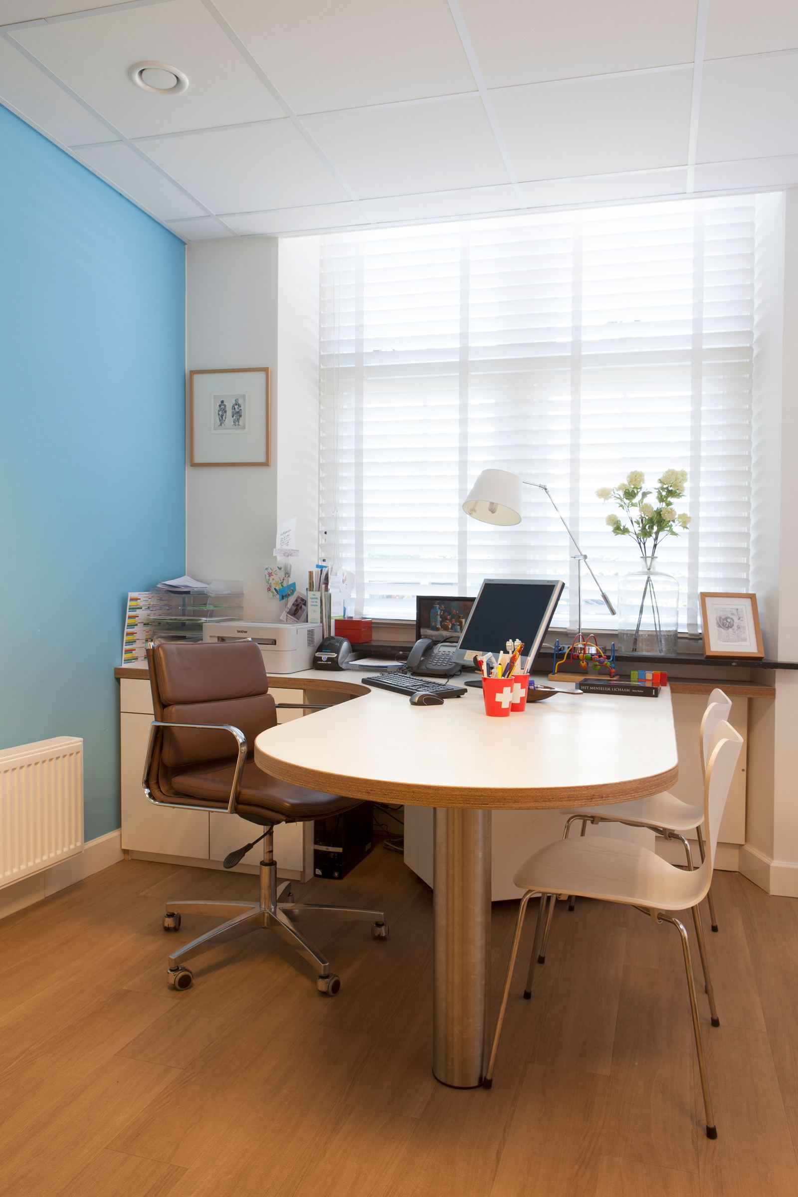Ronde spreekkamertafel met wit HPL blad en een ladenkast eronder.