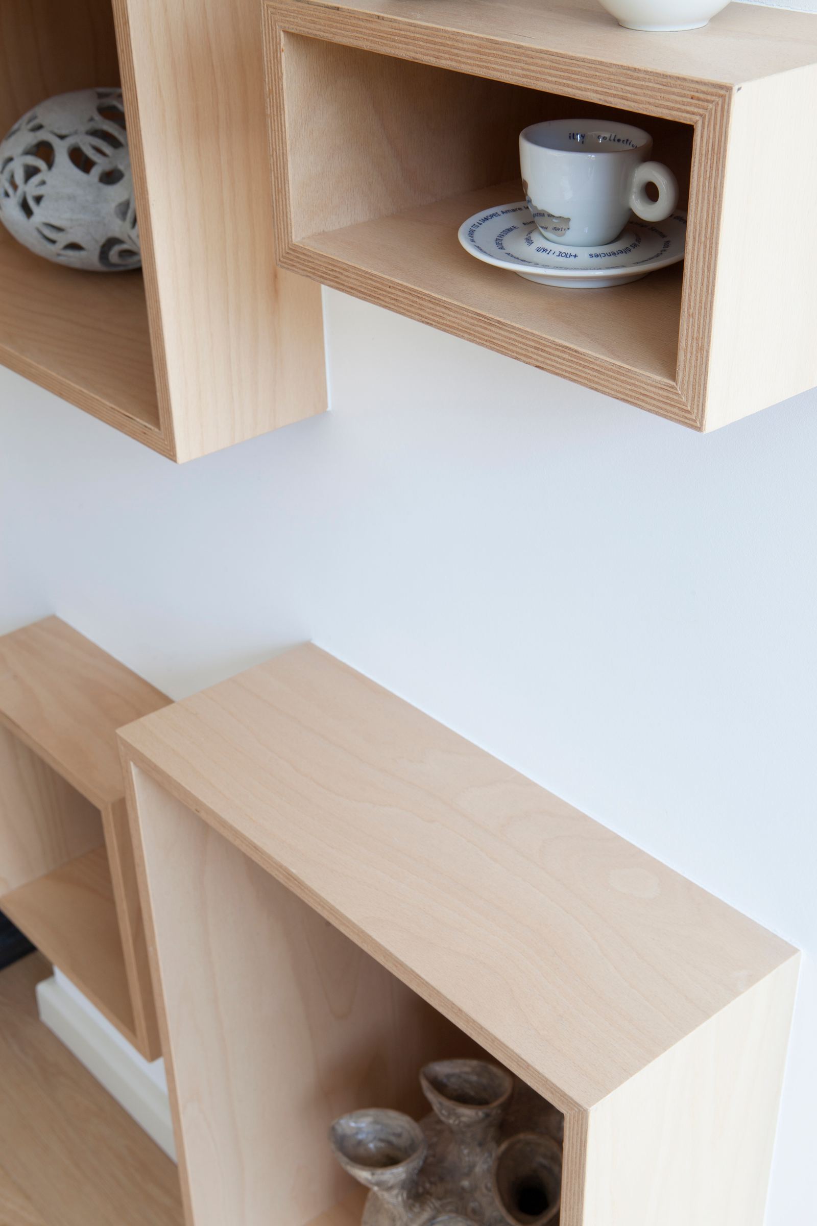 Detail van een berken multiplex vak met een espressokopje erin.